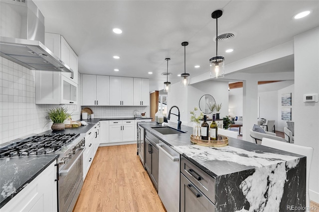 kitchen featuring a large island, white cabinetry, wall chimney exhaust hood, dark stone countertops, and appliances with stainless steel finishes