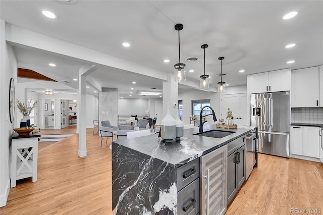 kitchen with pendant lighting, stainless steel appliances, wine cooler, a large island with sink, and sink