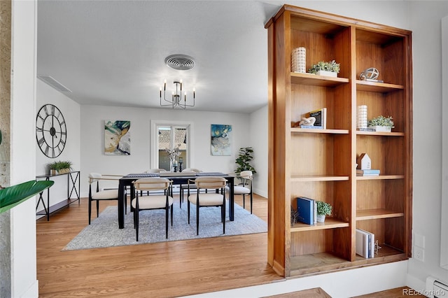 dining area featuring built in shelves, light hardwood / wood-style flooring, and a chandelier