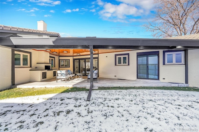 snow covered rear of property featuring ceiling fan, a patio, an outdoor hangout area, and an outdoor kitchen