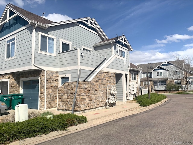 view of front facade featuring a residential view, board and batten siding, a balcony, and stone siding