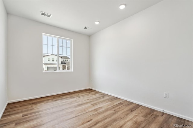 unfurnished room featuring wood finished floors, visible vents, and baseboards