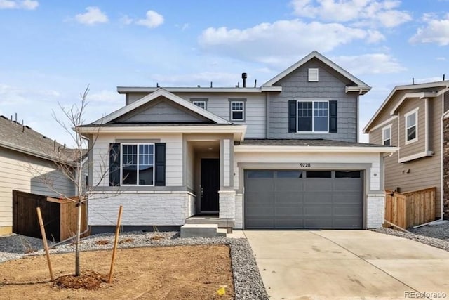 view of front facade featuring stone siding, concrete driveway, an attached garage, and fence