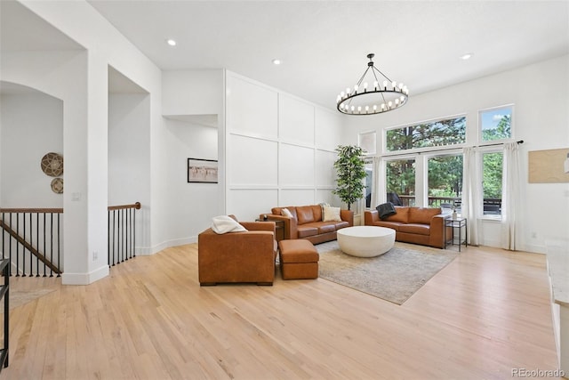 17912 Loverly Way, Monument, CO 80132 - living area with baseboards, a high ceiling, arched walkways, light wood-style flooring, and a notable chandelier