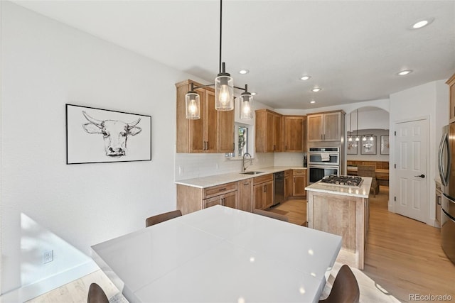 17912 Loverly Way, Monument, CO 80132 - kitchen with decorative backsplash, a kitchen island, arched walkways, a sink, and stainless steel appliances
