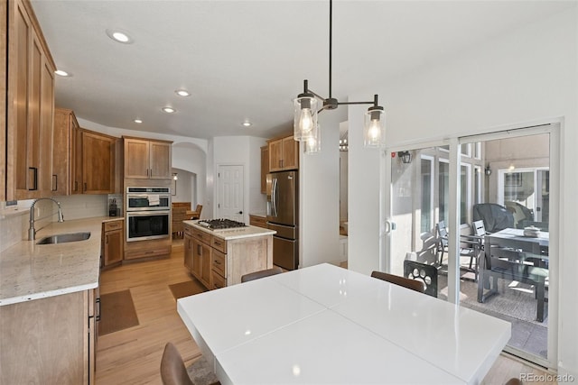 17912 Loverly Way, Monument, CO 80132 - kitchen with a sink, arched walkways, stainless steel appliances, backsplash, and a kitchen island