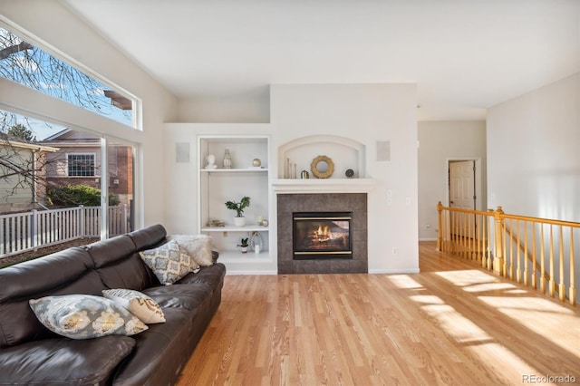 living room with a fireplace, light hardwood / wood-style flooring, and built in shelves