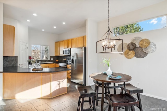 kitchen with pendant lighting, sink, tasteful backsplash, kitchen peninsula, and stainless steel appliances