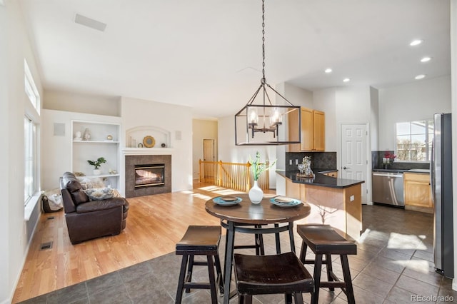 dining room with a fireplace, a chandelier, built in features, and dark wood-type flooring