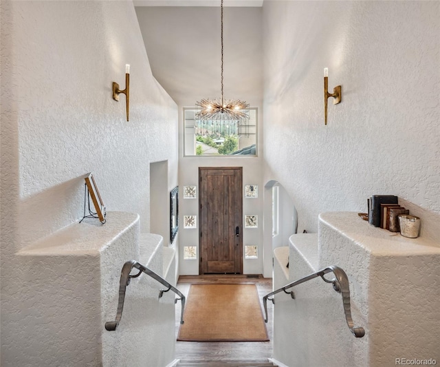 6338 Spotted Fawn Run, Littleton, CO 80125 - foyer entrance with a chandelier, wood finished floors, a textured wall, a towering ceiling, and stairs