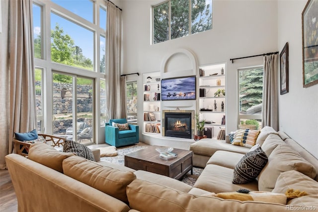6338 Spotted Fawn Run, Littleton, CO 80125 - living room featuring a high ceiling, a glass covered fireplace, built in shelves, and wood finished floors