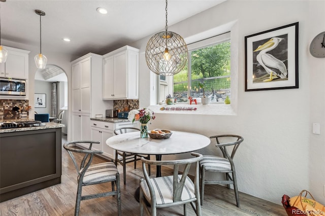 6338 Spotted Fawn Run, Littleton, CO 80125 - dining space featuring light wood-type flooring, recessed lighting, and arched walkways