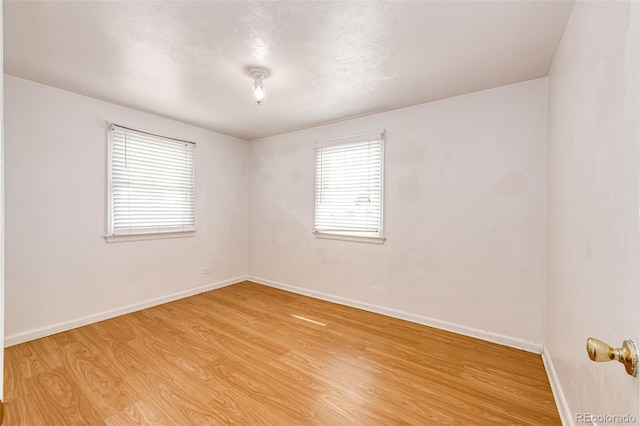 spare room with baseboards and light wood-style flooring