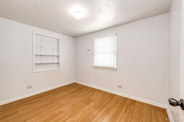 unfurnished room featuring baseboards and light wood-type flooring