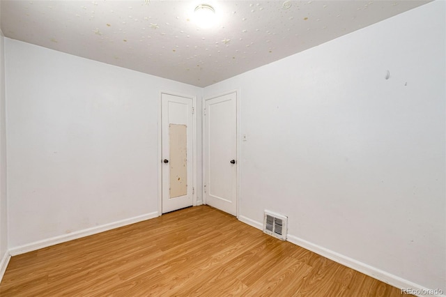 spare room featuring baseboards, visible vents, and light wood finished floors