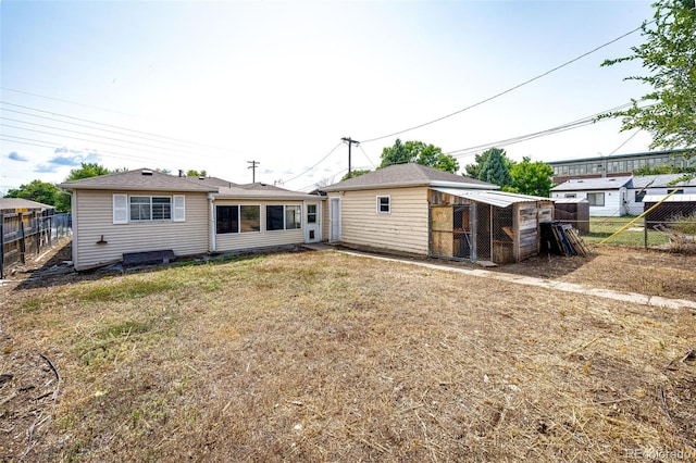 rear view of property featuring exterior structure, fence, and an outbuilding