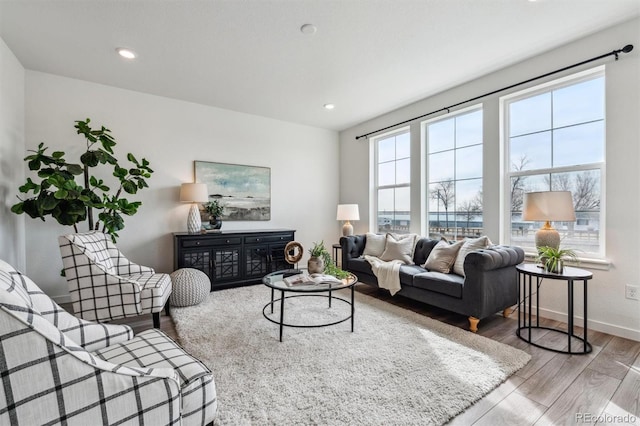 living area with baseboards, wood finished floors, and recessed lighting