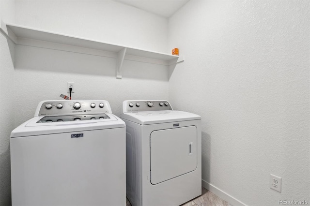 laundry area with laundry area, baseboards, washer and dryer, light wood-style floors, and a textured wall