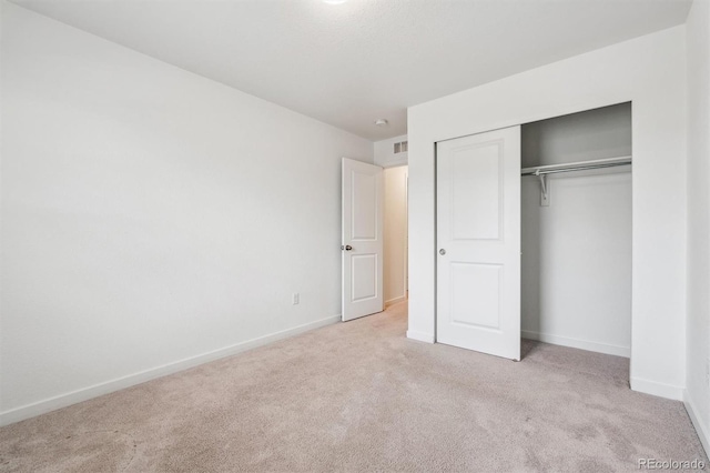 unfurnished bedroom featuring baseboards, visible vents, a closet, and carpet