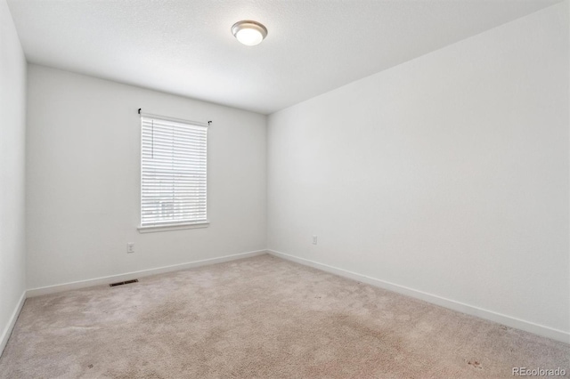 unfurnished room with light colored carpet, visible vents, and baseboards