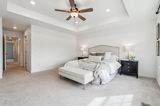 bedroom with light colored carpet and a raised ceiling