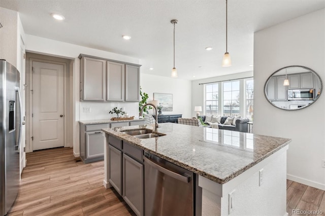 kitchen with gray cabinetry, a sink, stainless steel appliances, and light wood finished floors