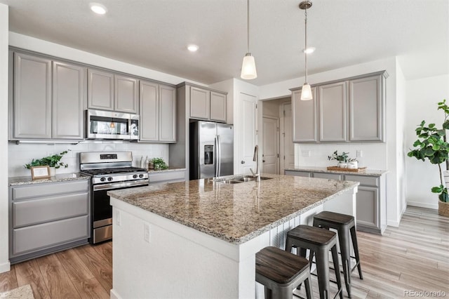 kitchen with gray cabinets, a sink, stainless steel appliances, and light wood-style flooring