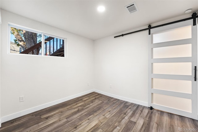 unfurnished room with hardwood / wood-style floors and a barn door