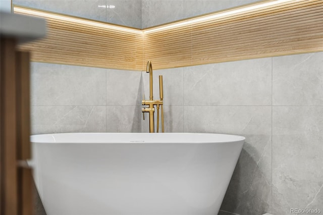 bathroom with a tub and tile walls