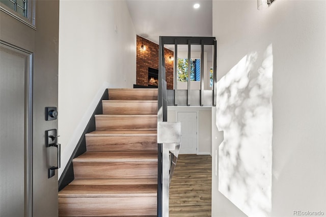 stairway featuring wood-type flooring and a fireplace