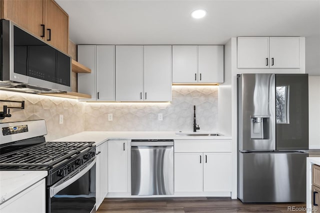 kitchen with white cabinets, stainless steel appliances, light stone countertops, and sink