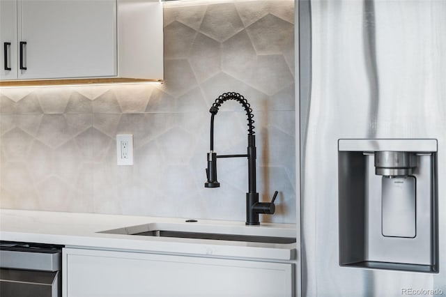 kitchen with tasteful backsplash, light stone counters, sink, and white cabinets