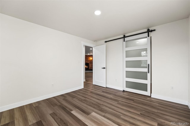 unfurnished bedroom featuring a barn door and dark hardwood / wood-style floors