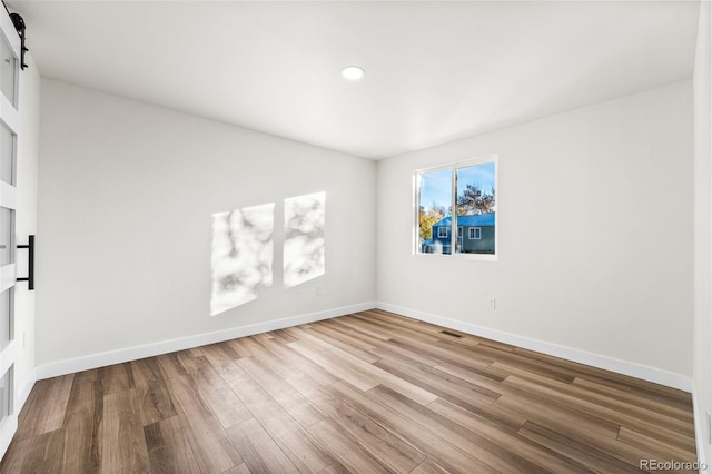 spare room with a barn door and light wood-type flooring