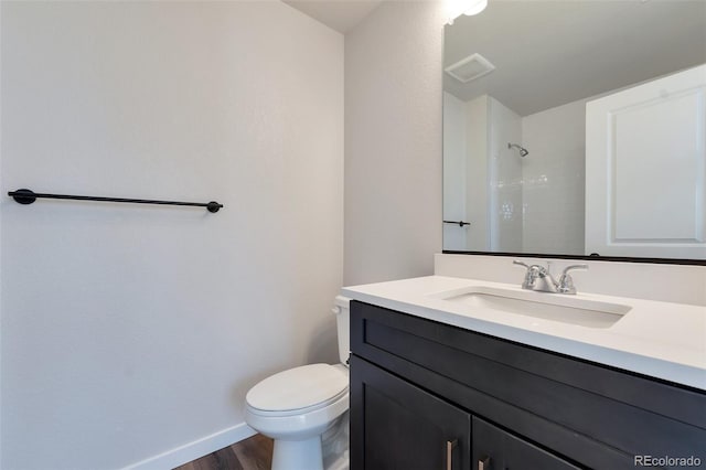 bathroom with toilet, walk in shower, vanity, and hardwood / wood-style flooring