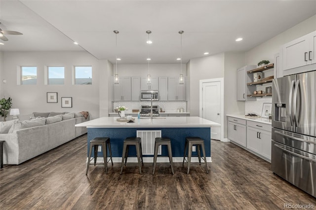 kitchen featuring open shelves, dark wood-style flooring, a sink, stainless steel appliances, and a kitchen bar