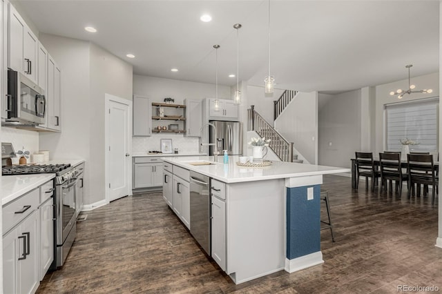 kitchen with a sink, open shelves, stainless steel appliances, dark wood-style flooring, and hanging light fixtures