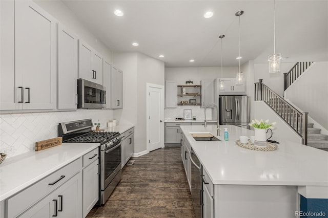 kitchen with a sink, open shelves, light countertops, stainless steel appliances, and a kitchen island with sink