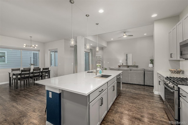 kitchen featuring dark wood finished floors, a sink, light countertops, appliances with stainless steel finishes, and open floor plan