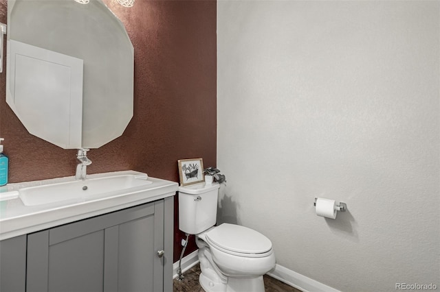 half bathroom featuring toilet, vanity, and baseboards