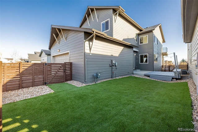 rear view of house featuring a garage, a lawn, central air condition unit, and a fenced backyard