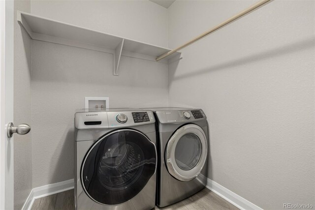 washroom featuring baseboards, wood finished floors, laundry area, and washer and clothes dryer