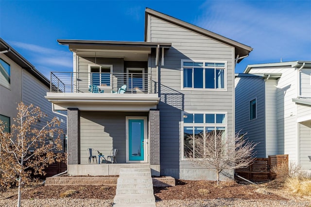 contemporary home with brick siding, a porch, and a balcony