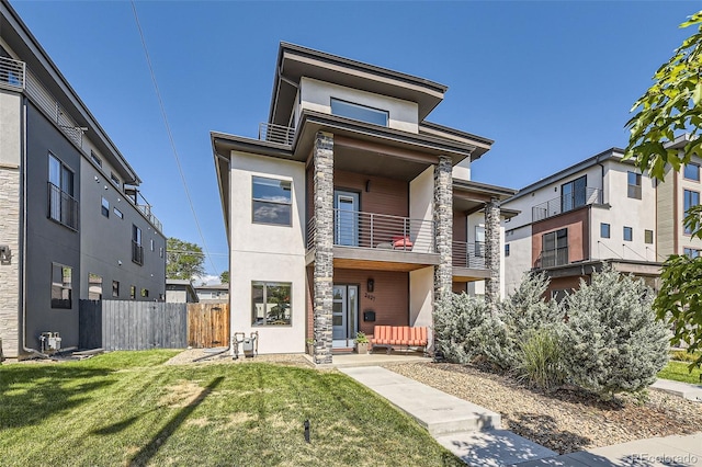 view of front facade with a front yard, fence, and stucco siding