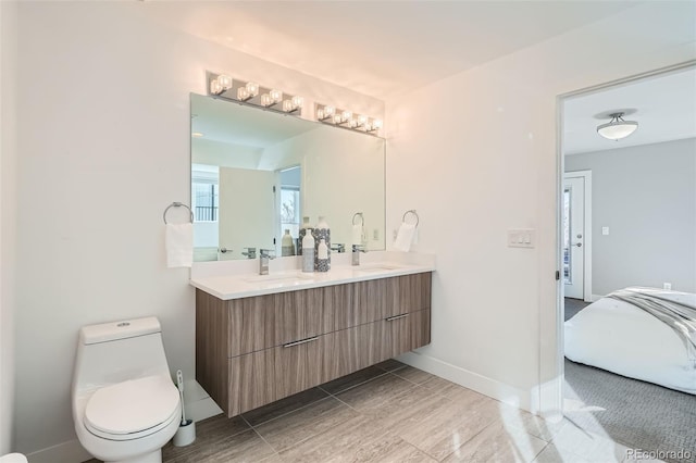 bathroom featuring baseboards, a sink, toilet, and double vanity