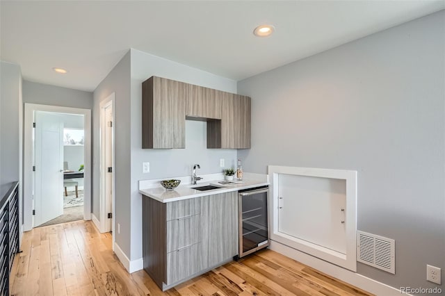 kitchen featuring light wood-style floors, beverage cooler, modern cabinets, and visible vents