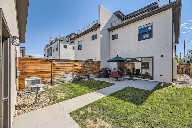 rear view of property with a lawn, a patio, a fenced backyard, cooling unit, and stucco siding