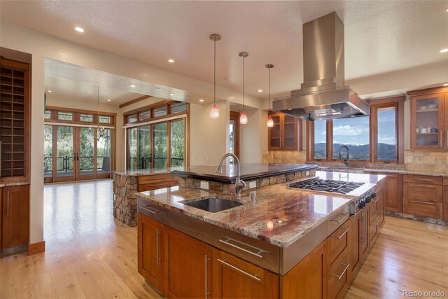180 Outpost Ln, Evergreen, CO 80439 - kitchen featuring island exhaust hood, a sink, brown cabinetry, a spacious island, and light wood-type flooring