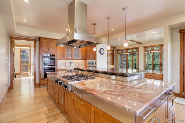 180 Outpost Ln, Evergreen, CO 80439 - kitchen with appliances with stainless steel finishes, island exhaust hood, light wood-type flooring, baseboards, and brown cabinetry