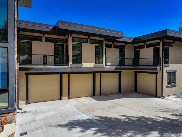 180 Outpost Ln, Evergreen, CO 80439 - view of front of house featuring a balcony, driveway, stucco siding, and an attached garage